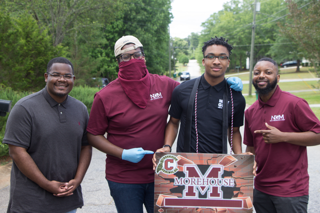 Members of Next Gen pose with a sign for Morehouse College