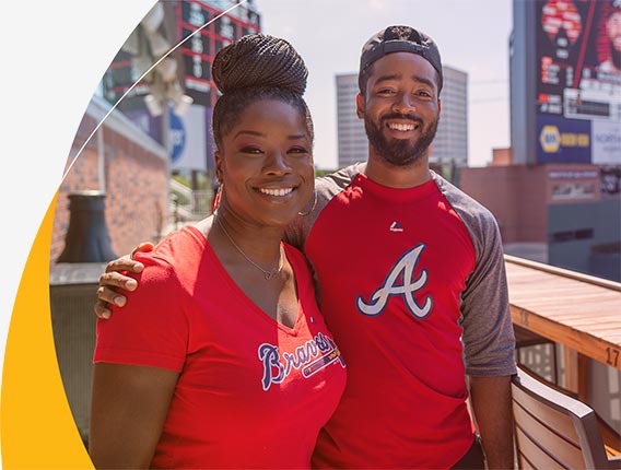 Two young Gas South employees wearing Atlanta Braves t-shirts smile for the camera during a company outing at Truist Park