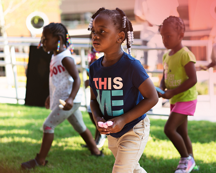 3 young girls play outdoors with chalk at the YMCA