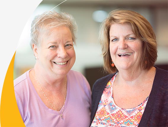 Two friendly, smiling women who are Gas South call center employees at the Atlanta-based office