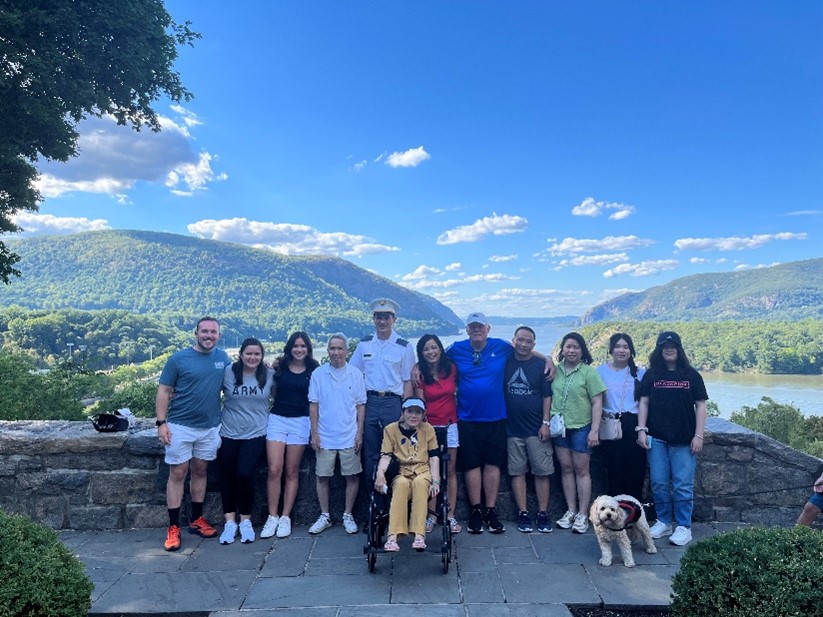 Twelve people in front of a lake with mountains in the background.